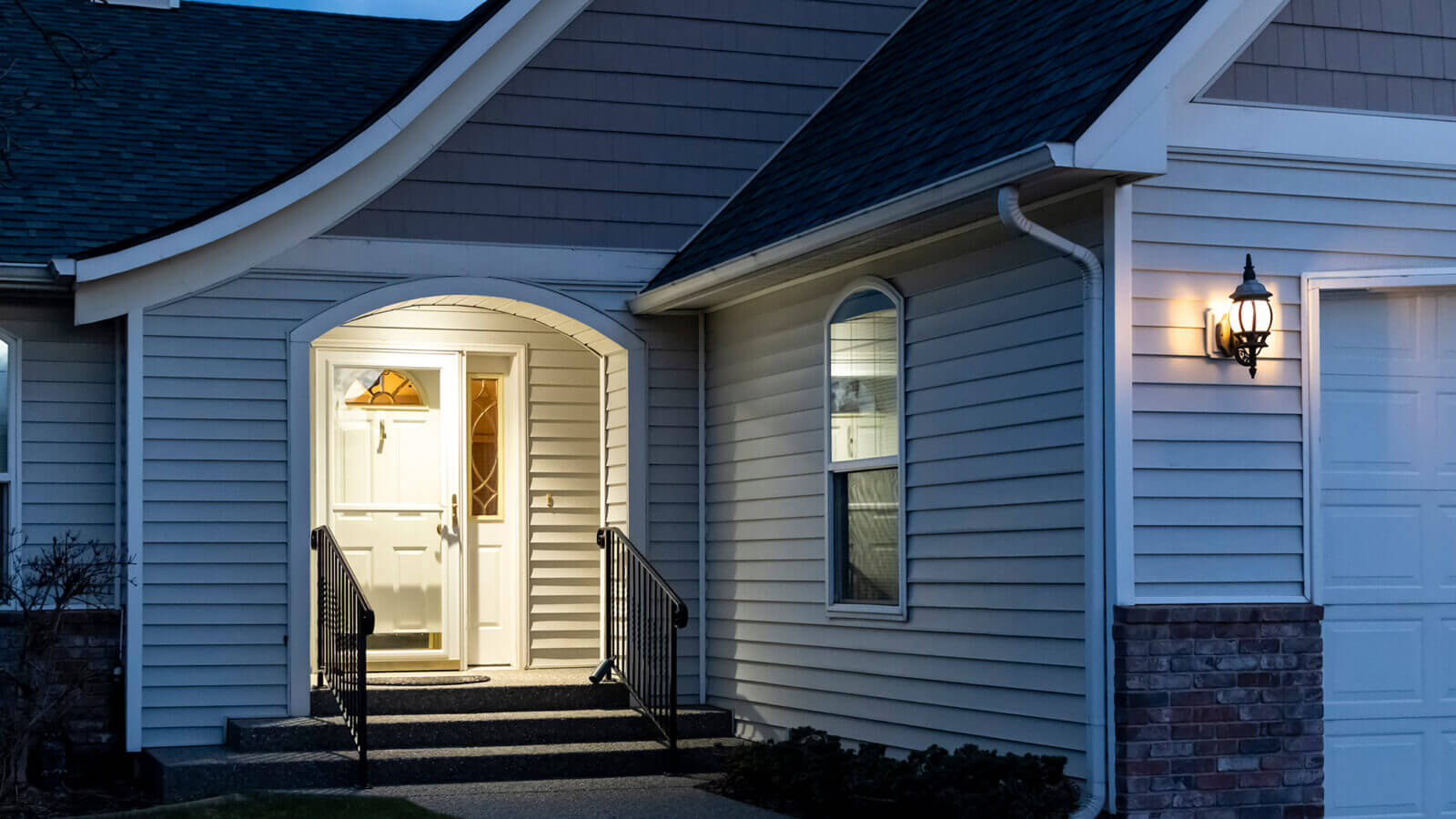 A home's front porch with a lockbox attached to the railing of t