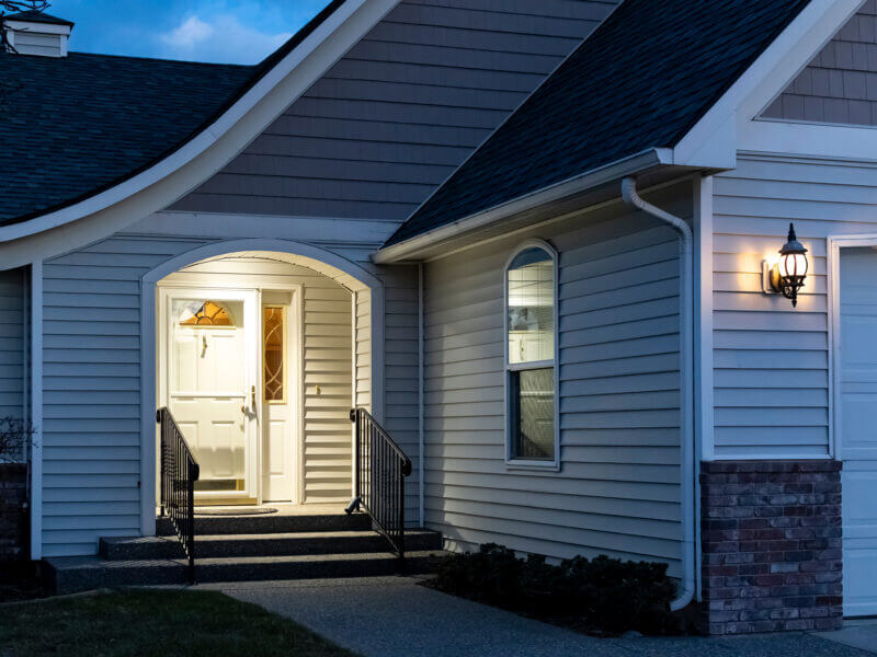 A home's front porch with a lockbox attached to the railing of t